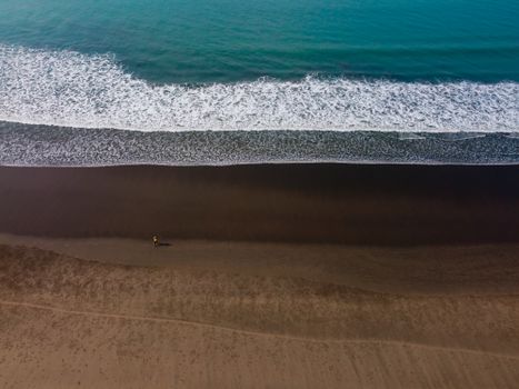 Aerial perspective of Cox's Bazar, capturing serene waves and a solitary beach walker.