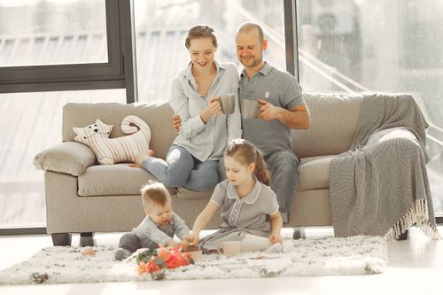 Free Cheerful family wearing casual clothes sitting in living room while playing and drinking tea during weekend at home in morning Stock Photo