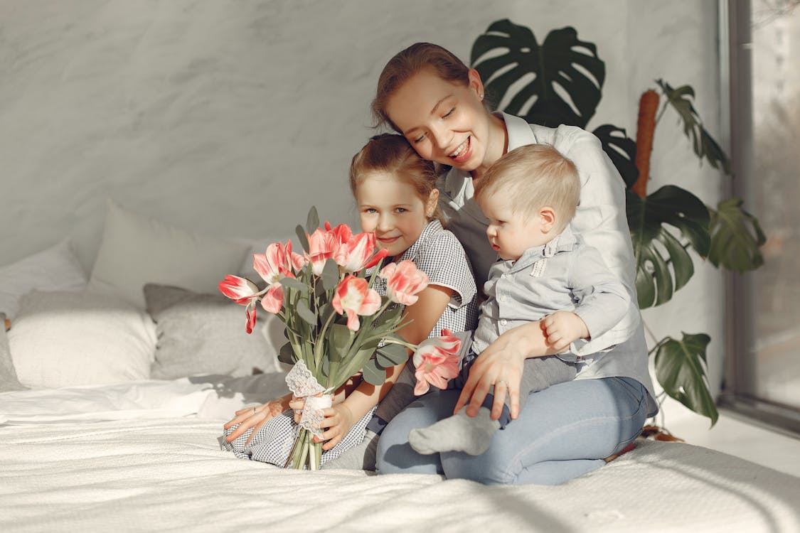Mother with children sitting on bed at home