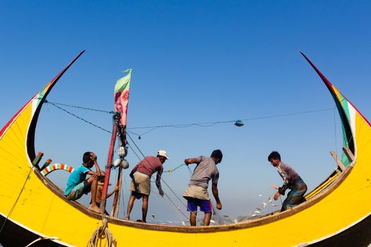 Fishermen working on a colorful fishing boat under a clear blue sky at Cox's Bazar, Bangladesh.