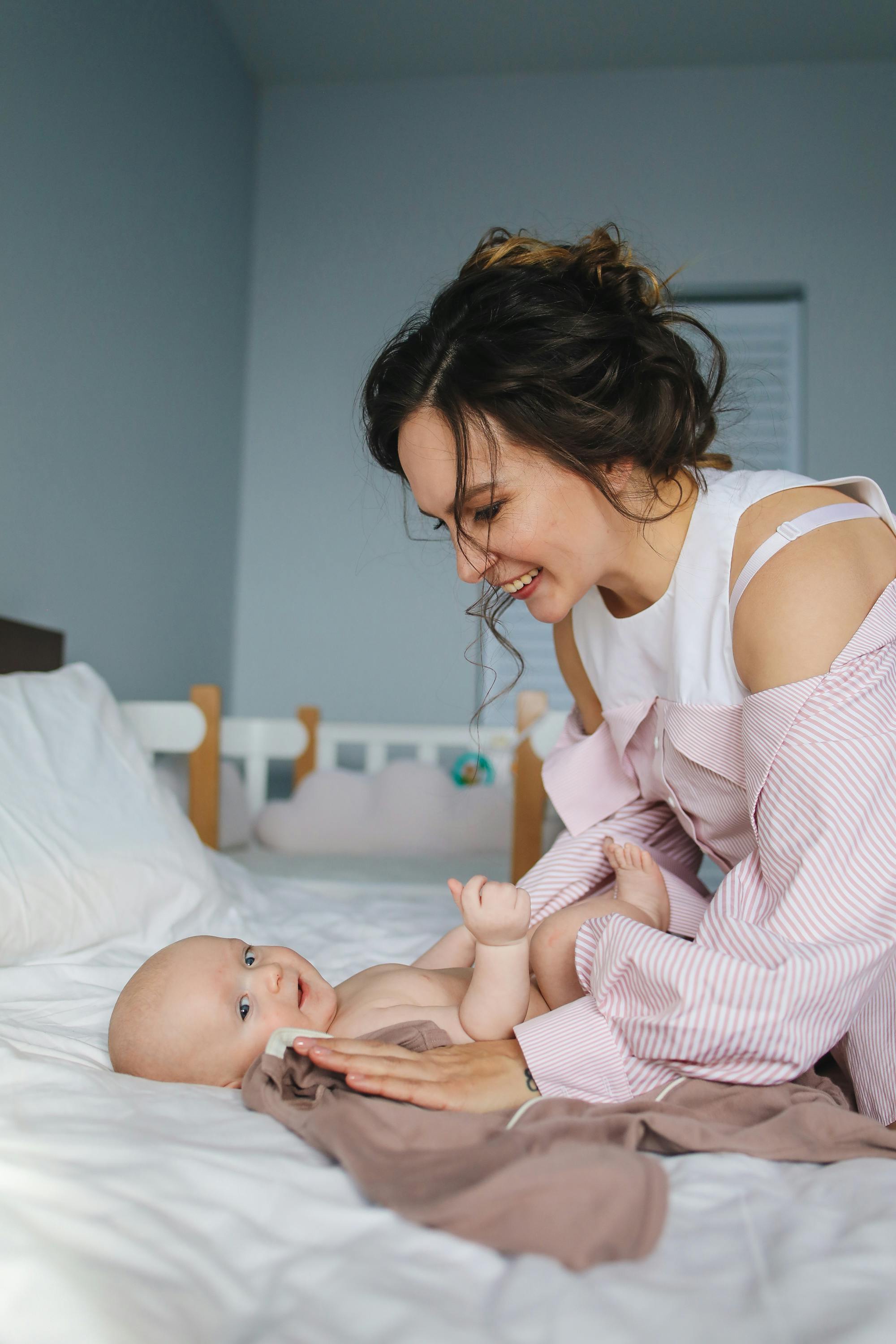 smiling mother playing with her baby on bed