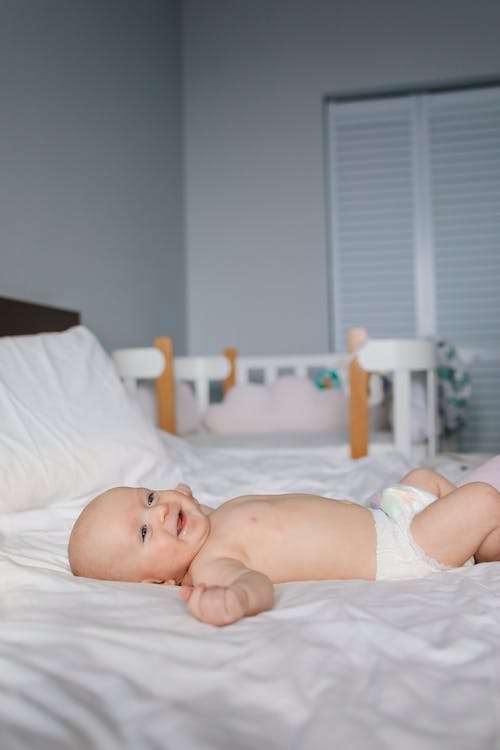 Baby in White Diaper Lying on Bed