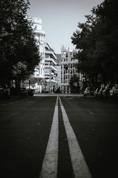 Black and white photo of an empty street in Madrid, Spain, showcasing urban architecture.