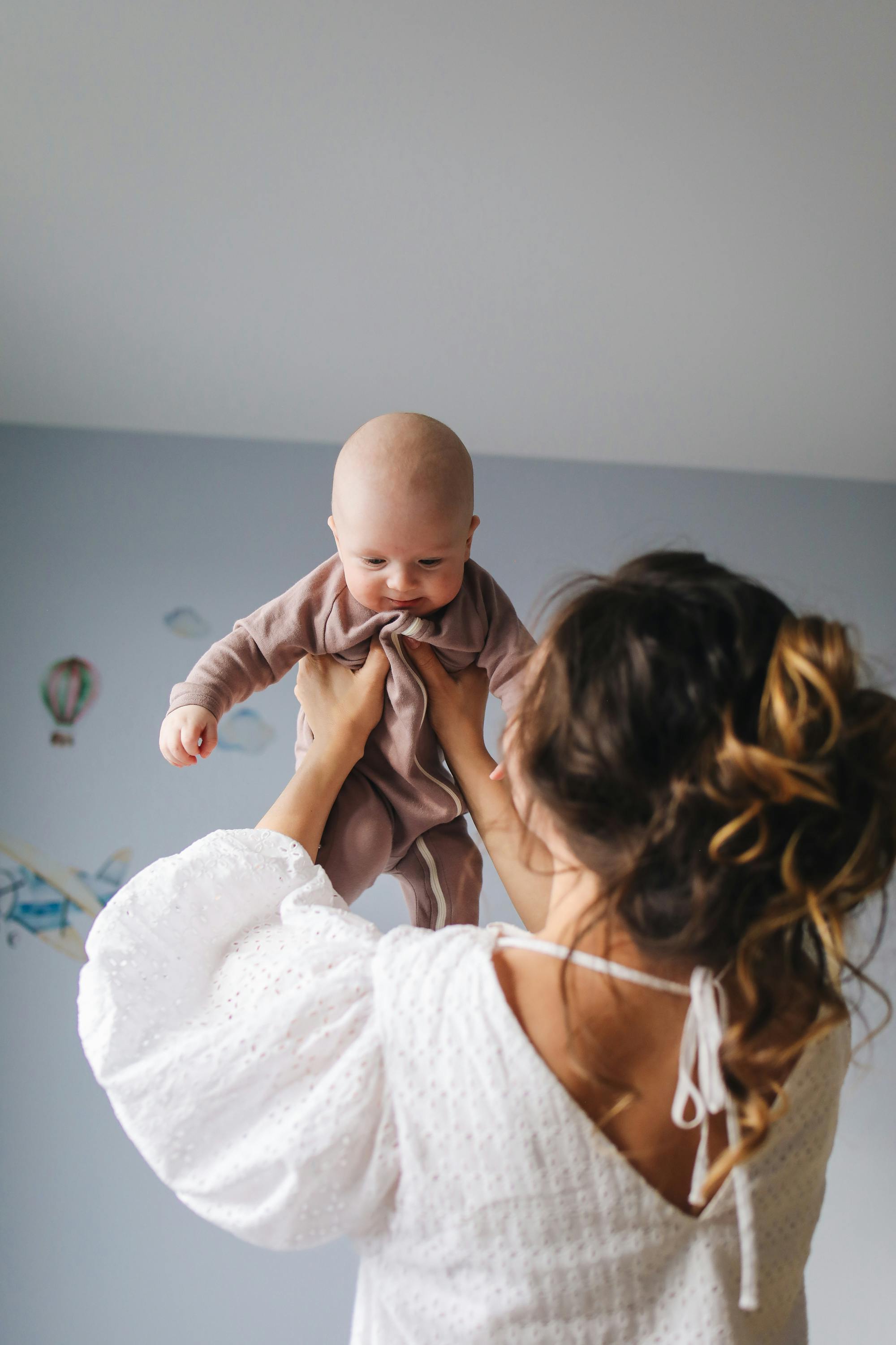 woman in white top carrying baby