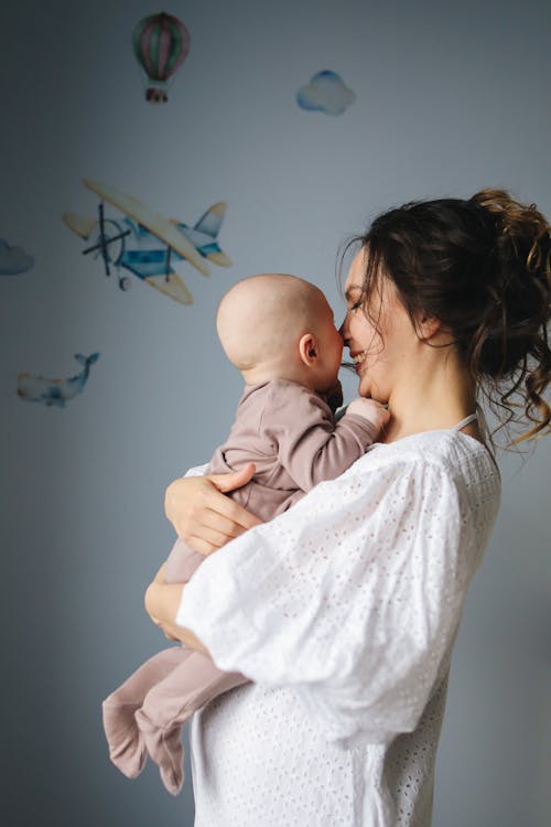 Free Woman in White Top Carrying Baby Stock Photo