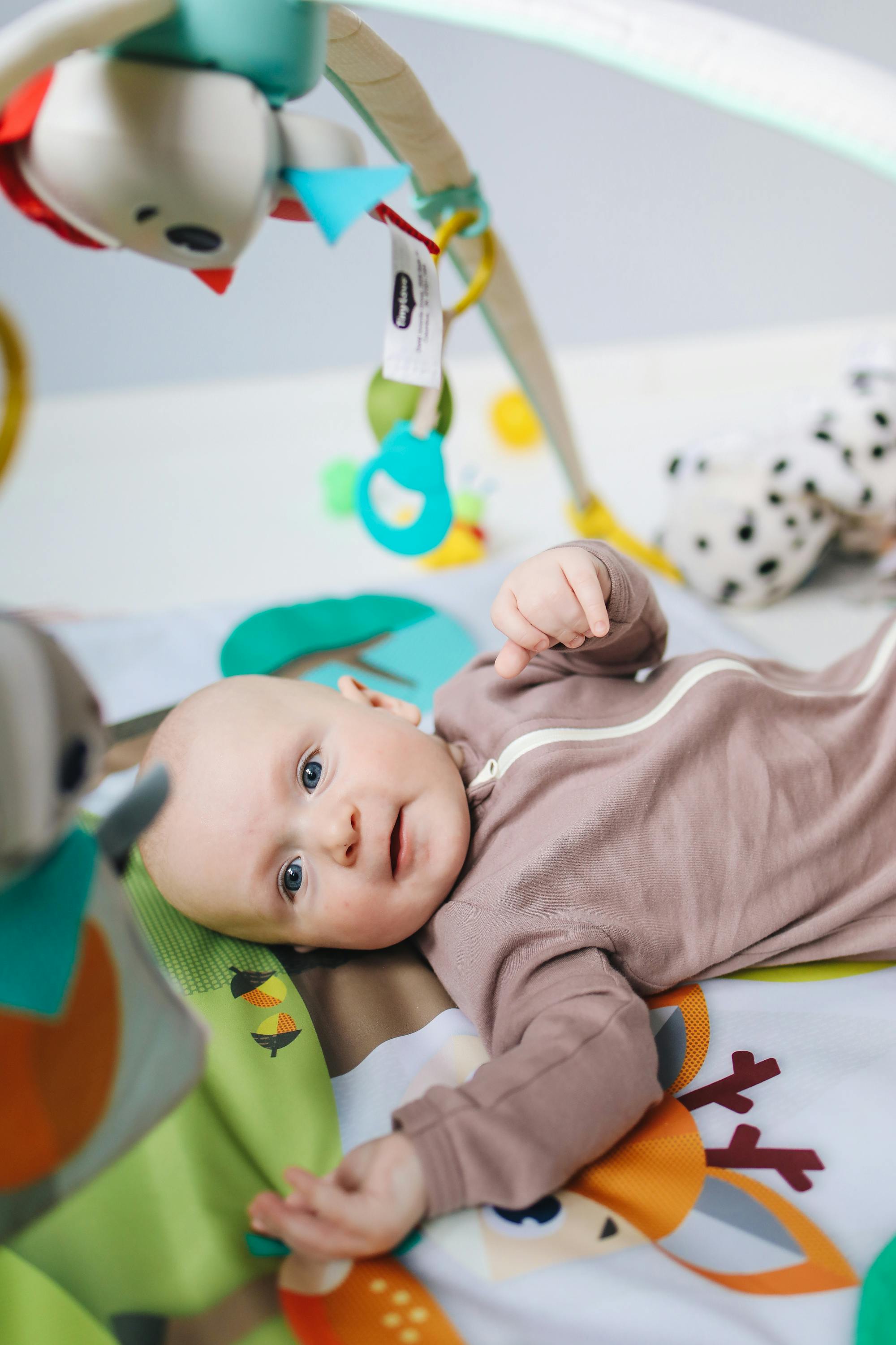 Baby in Brown Onesie Lying on Bed · Free Stock Photo