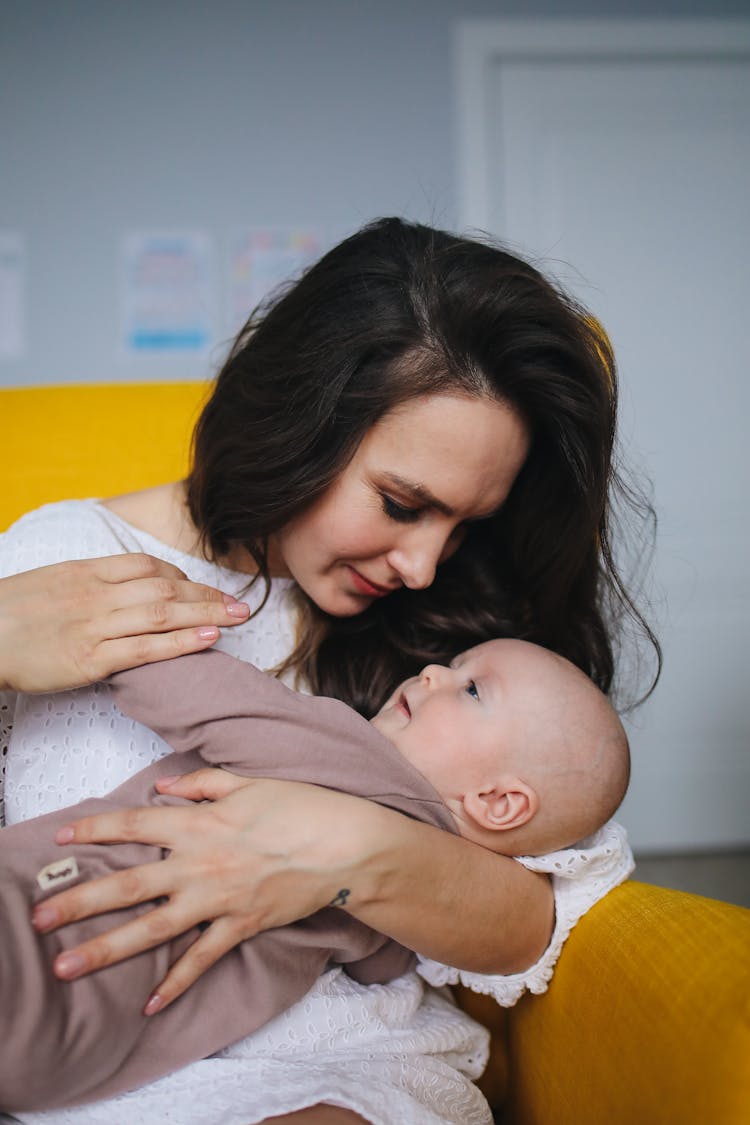 Woman In White Dress Carrying Baby Wearing Brown Onesie