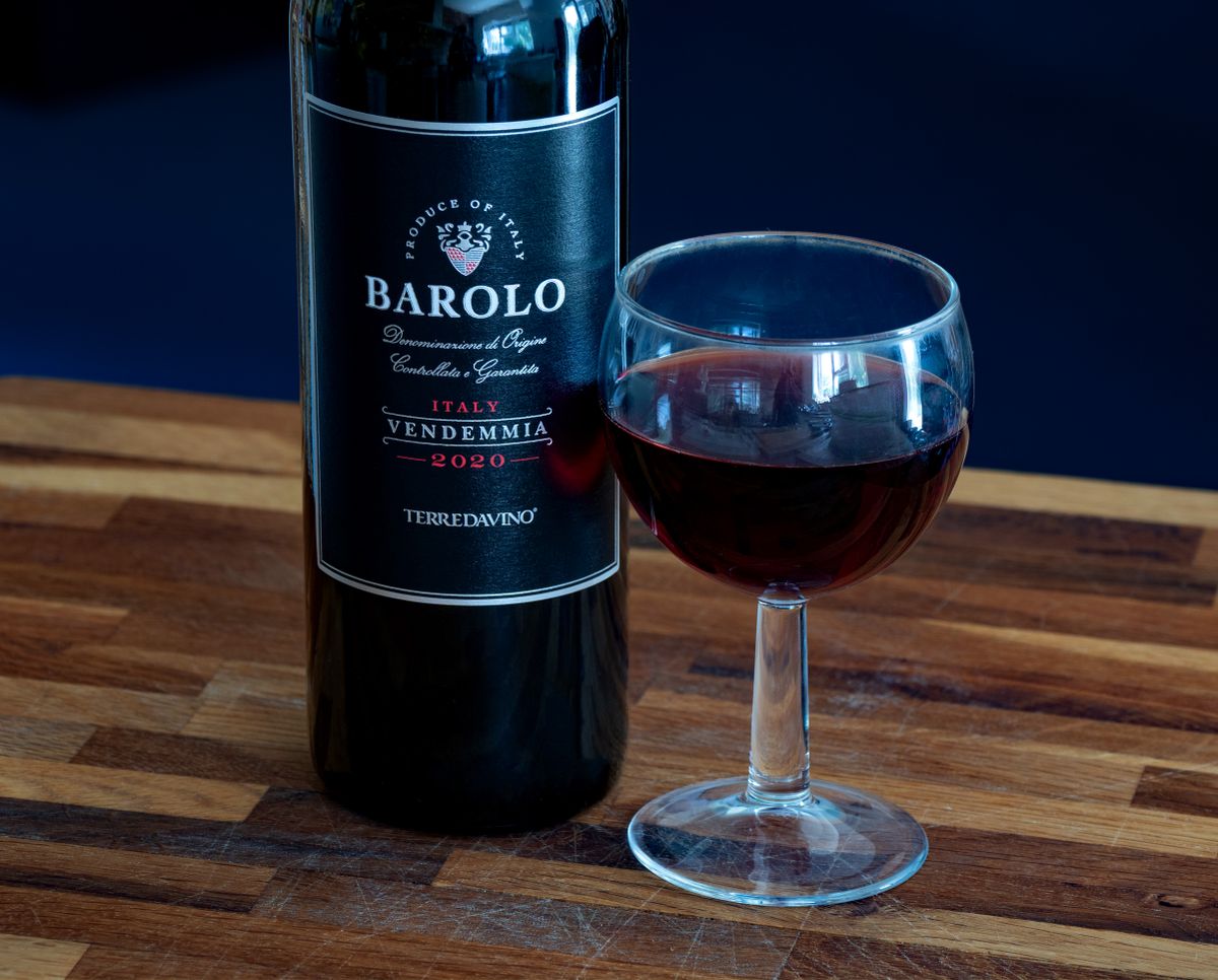 Sticla de Barolo si un pahar de vin rosu pe masa de lemn