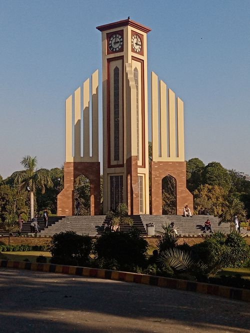 Free The iconic Faisalabad Clock Tower under a clear blue sky, surrounded by greenery. Stock Photo