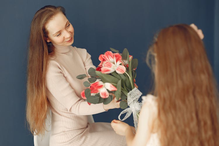 Happy Daughter Giving Flowers To Mother