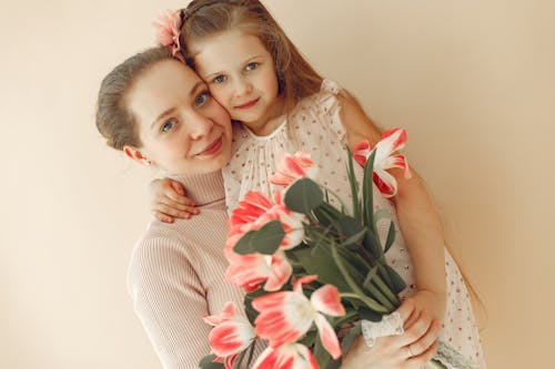 Woman In Knit Sweater Holding Girl In White Floral Dress