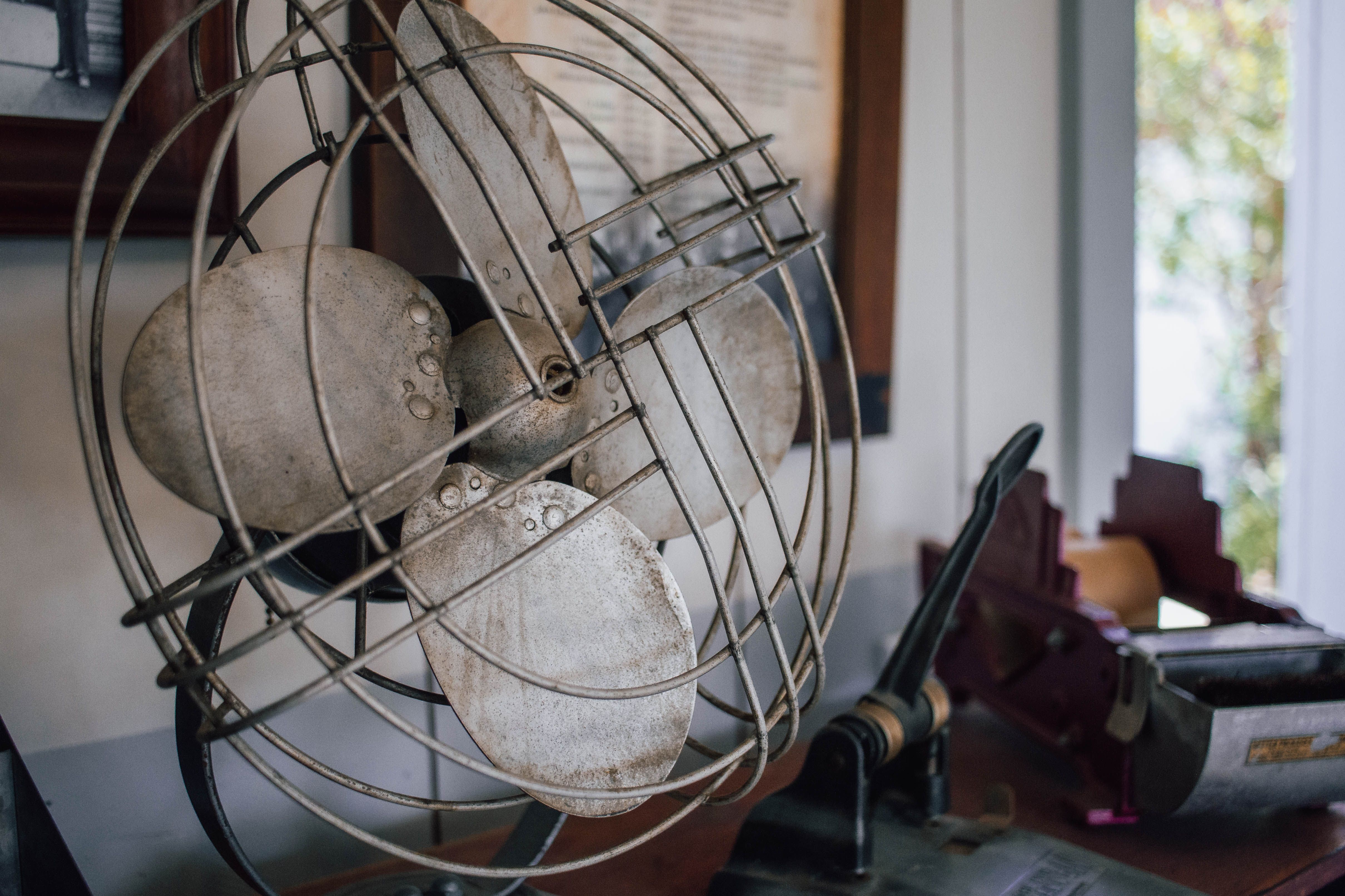 A close-up of a vintage metal fan on a desk with office supplies, creating a nostalgic vibe.