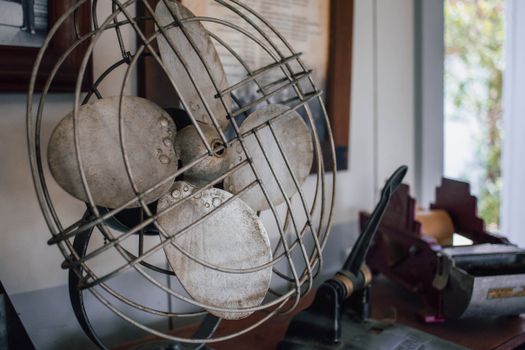 A close-up of a vintage metal fan on a desk with office supplies, creating a nostalgic vibe.