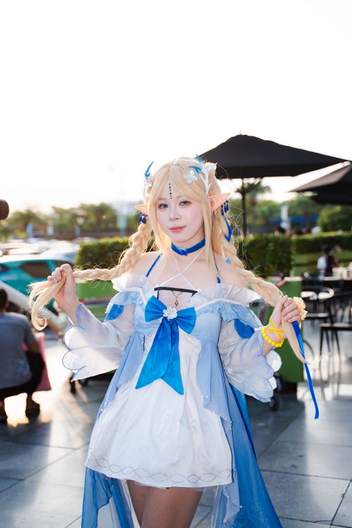 Free Cosplayer dressed as a fantasy elf character with blonde braids and blue dress posing outdoors. Stock Photo