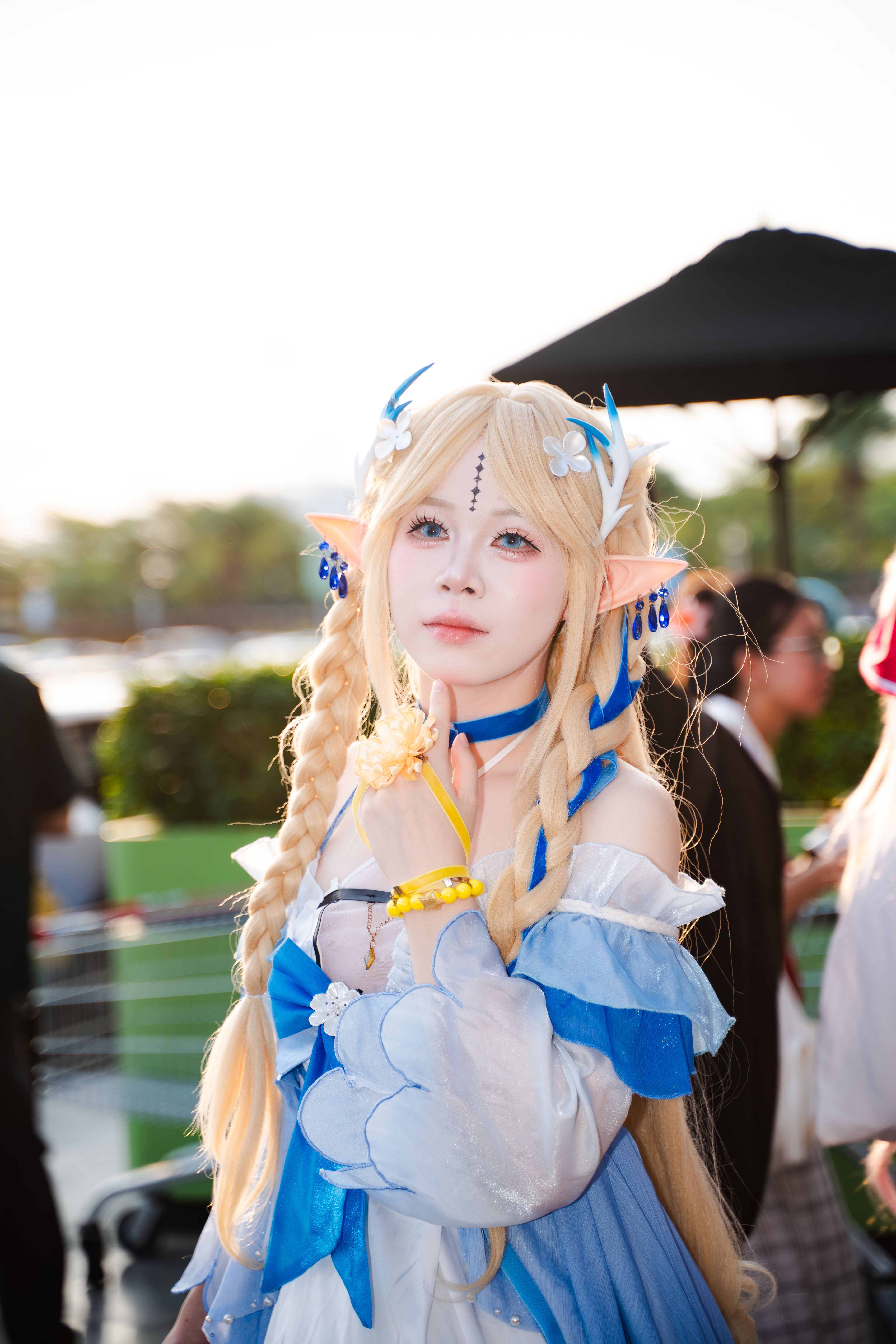 A cosplayer wearing an elaborate fantasy elf costume at an outdoor event, showcasing creativity and craftsmanship.