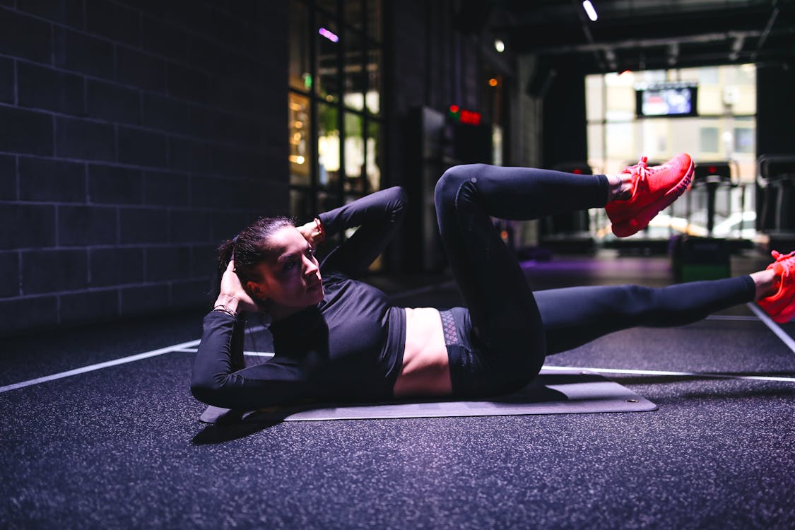 Strong sportswoman doing criss cross exercise on mat