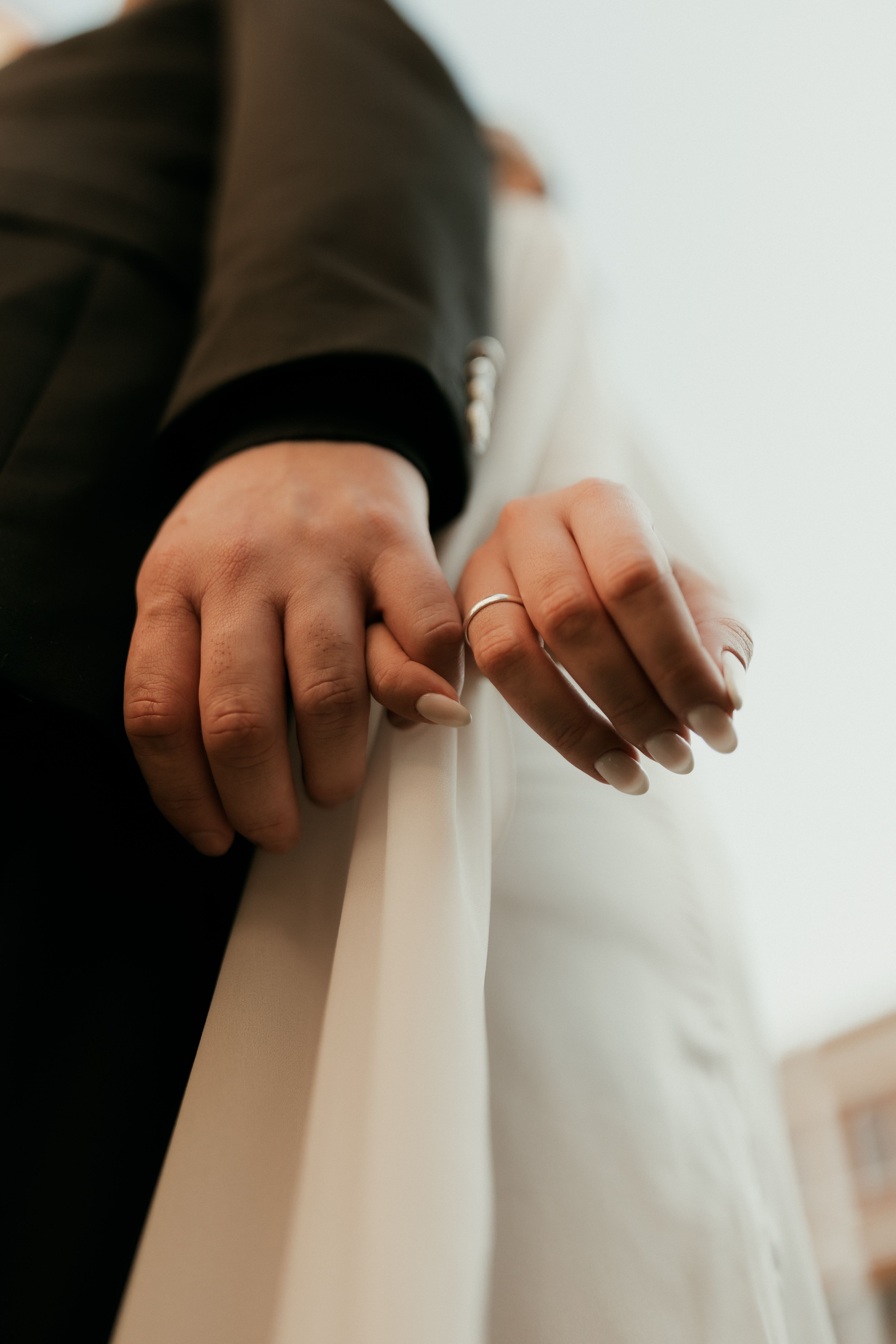 Romantic close-up of a couple holding hands on their wedding day, symbolizing love and unity.