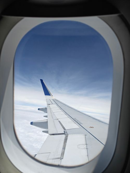 Free A peaceful view of an airplane wing against a clear blue sky from the cabin window. Stock Photo