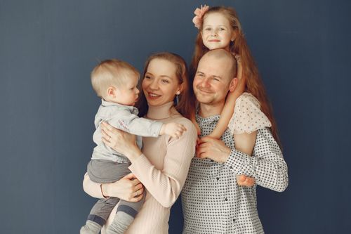 Free A joyful family portrait showcasing parents and their two children, expressing love and togetherness. Stock Photo