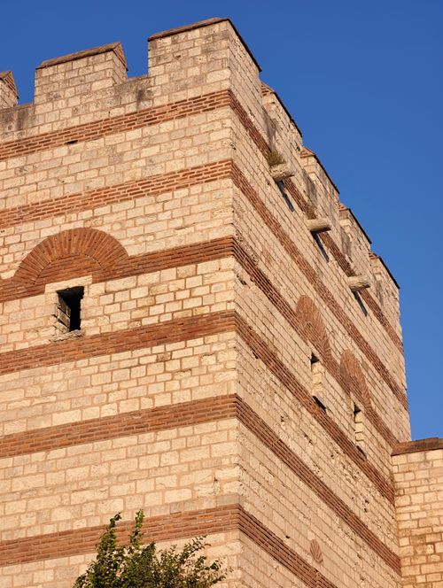 Free Historic stone tower with brick accents against a clear blue sky, showcasing medieval architecture. Stock Photo