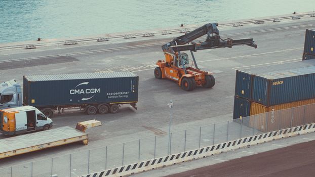 View of a busy container terminal with trucks and forklifts managing cargo under daylight.