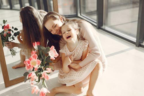 Photo of Mother and Daughter Sitting on the Floor