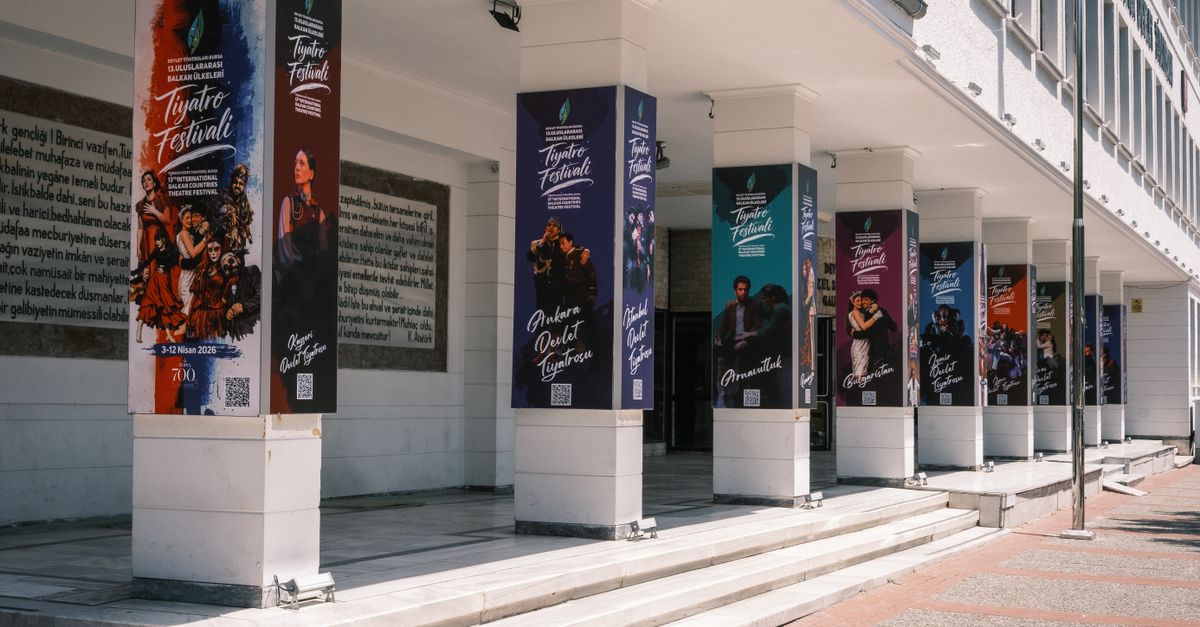 Colorful theatre festival posters on building columns outdoors in daylight.