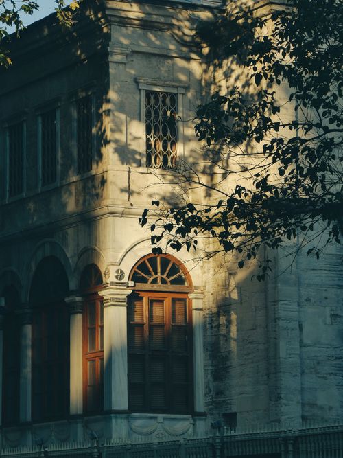 Free Sunlit historic building in Istanbul with arched windows and leafy shadows creating a serene ambiance. Stock Photo