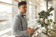 一位穿着时尚服装的男子在阳光照射的窗边摆出姿势，显得优雅而专业