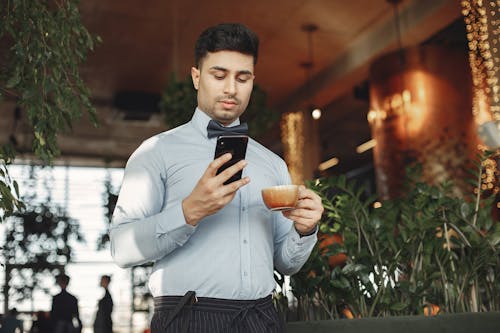 Man In Dress Shirt Holding Black Smartphone
