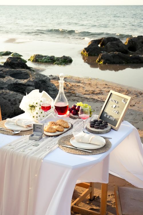 Free Elegant beachside table with wine and desserts, perfect for romance. Stock Photo