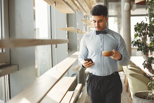 Free Man In Blue Dress Shirt And Black Dress Pants Holding Smartphone Stock Photo