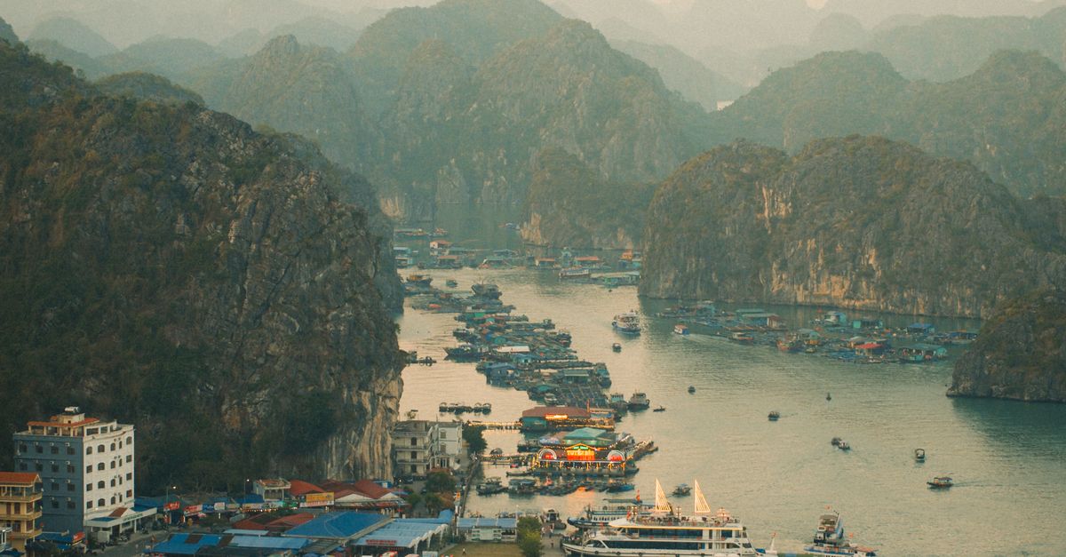 Captivating aerial view of a coastal village amid karst islets in a serene bay at daybreak.