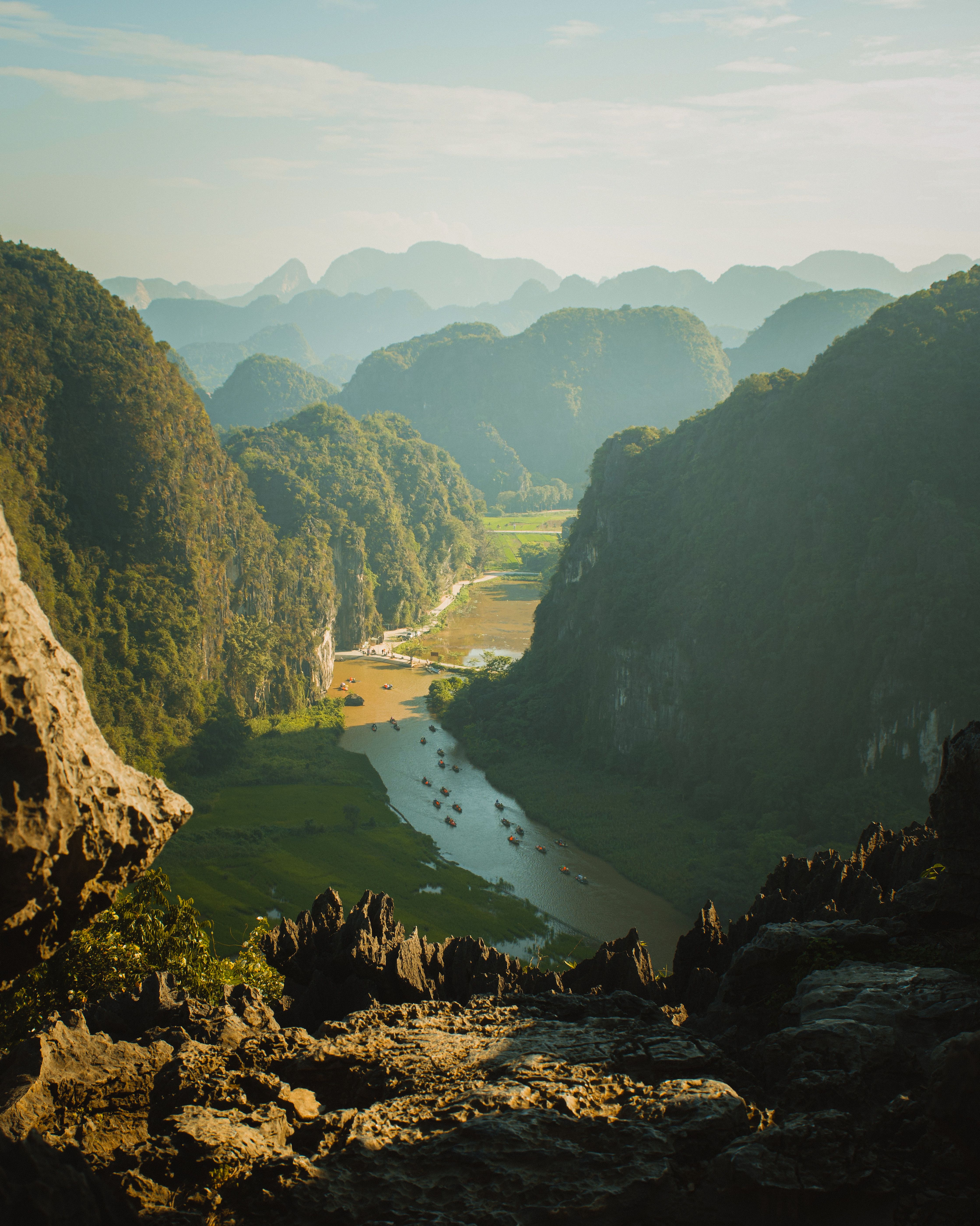 A stunning view of a river valley surrounded by dramatic limestone mountains under a clear blue sky.
