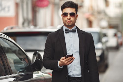 Man In Black Suit Jacket Holding Smartphone