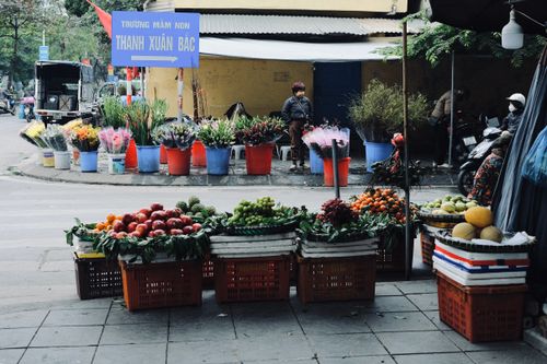 Free Colorful street market scene in Vietnam featuring fresh fruits, vegetables, and flowers. Stock Photo