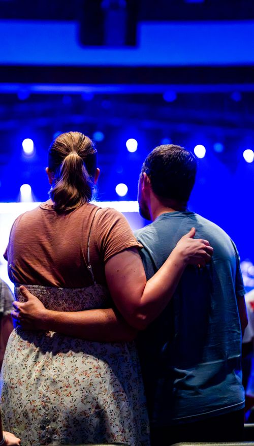 Free A couple embraces while enjoying a live music concert indoors. Captured from behind, the scene exudes warmth and connection. Stock Photo