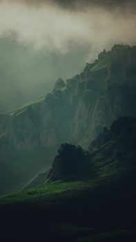 Lush green mountains under a misty sky in Chechnya, showcasing natural beauty and serenity.