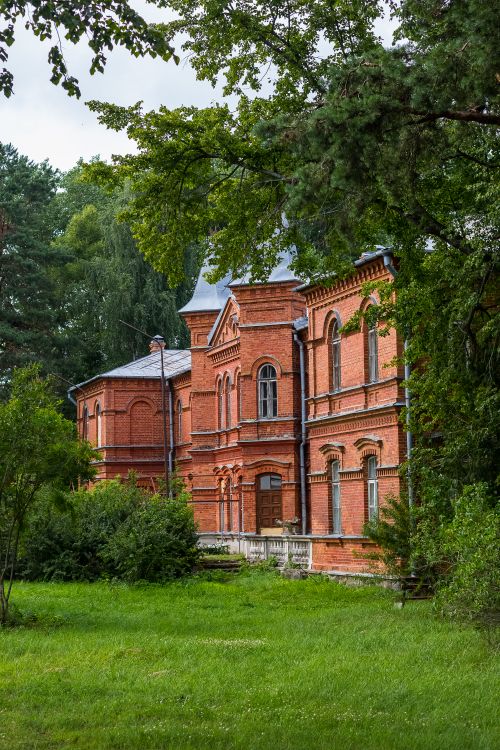 Free Charming red brick building nestled amidst dense green trees, showcasing architectural elegance. Stock Photo