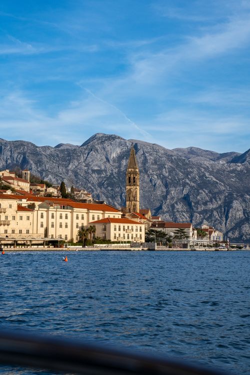 Free Picturesque Perast village with historic church tower against rugged mountains in Montenegro. Stock Photo