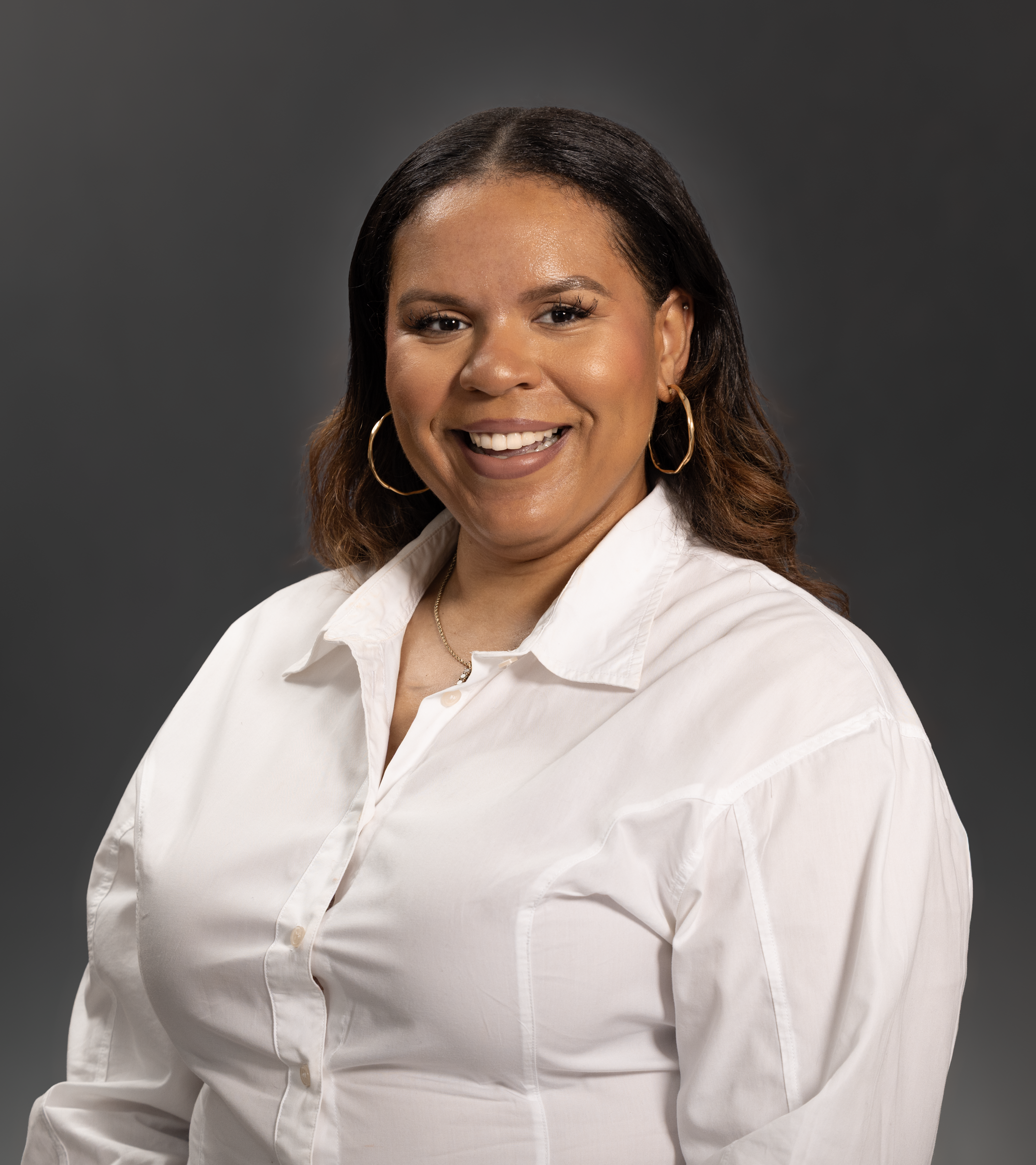 Smiling woman in a white shirt posing in a studio setting.