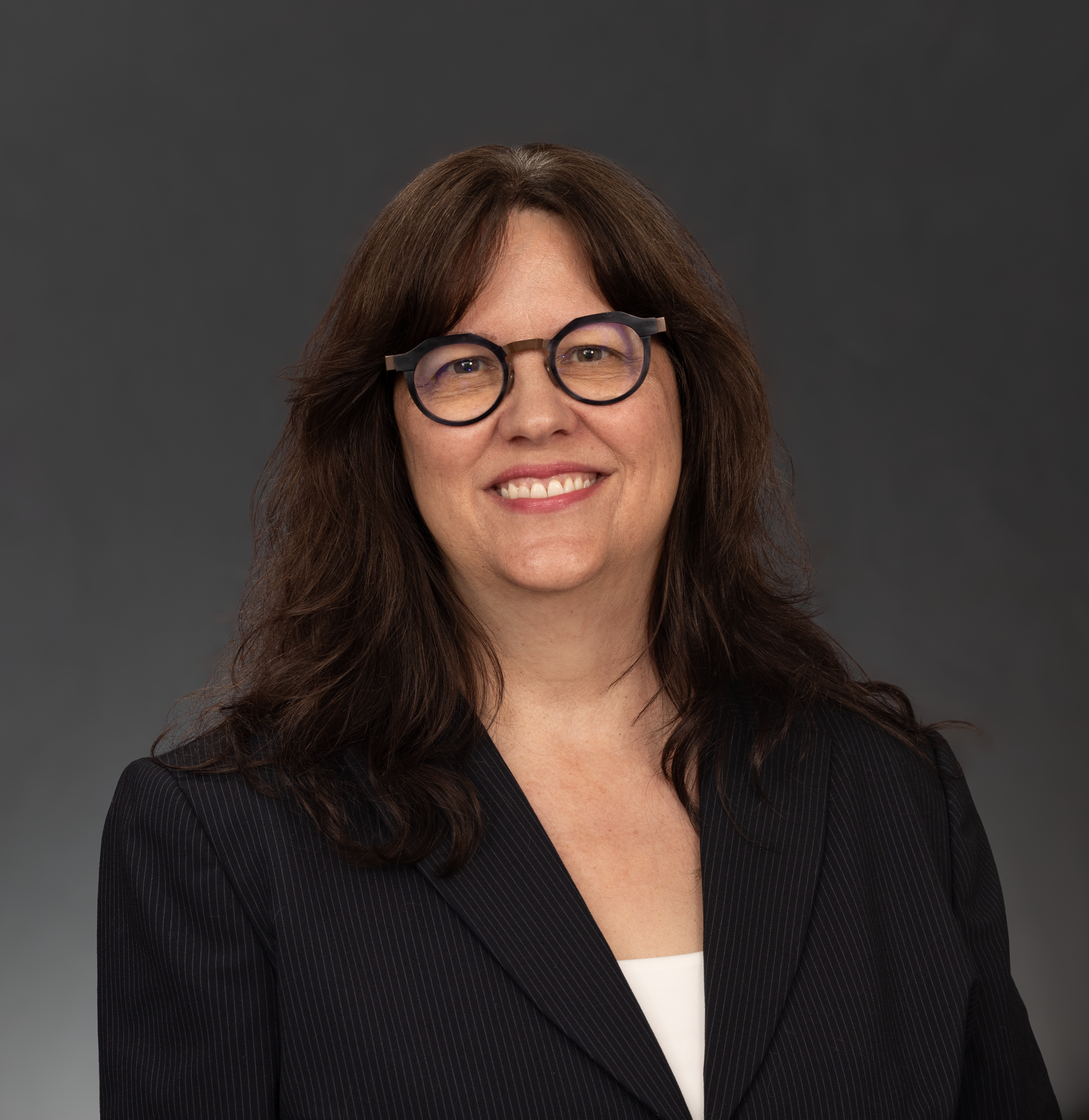 Portrait of a smiling businesswoman wearing glasses against a neutral background.