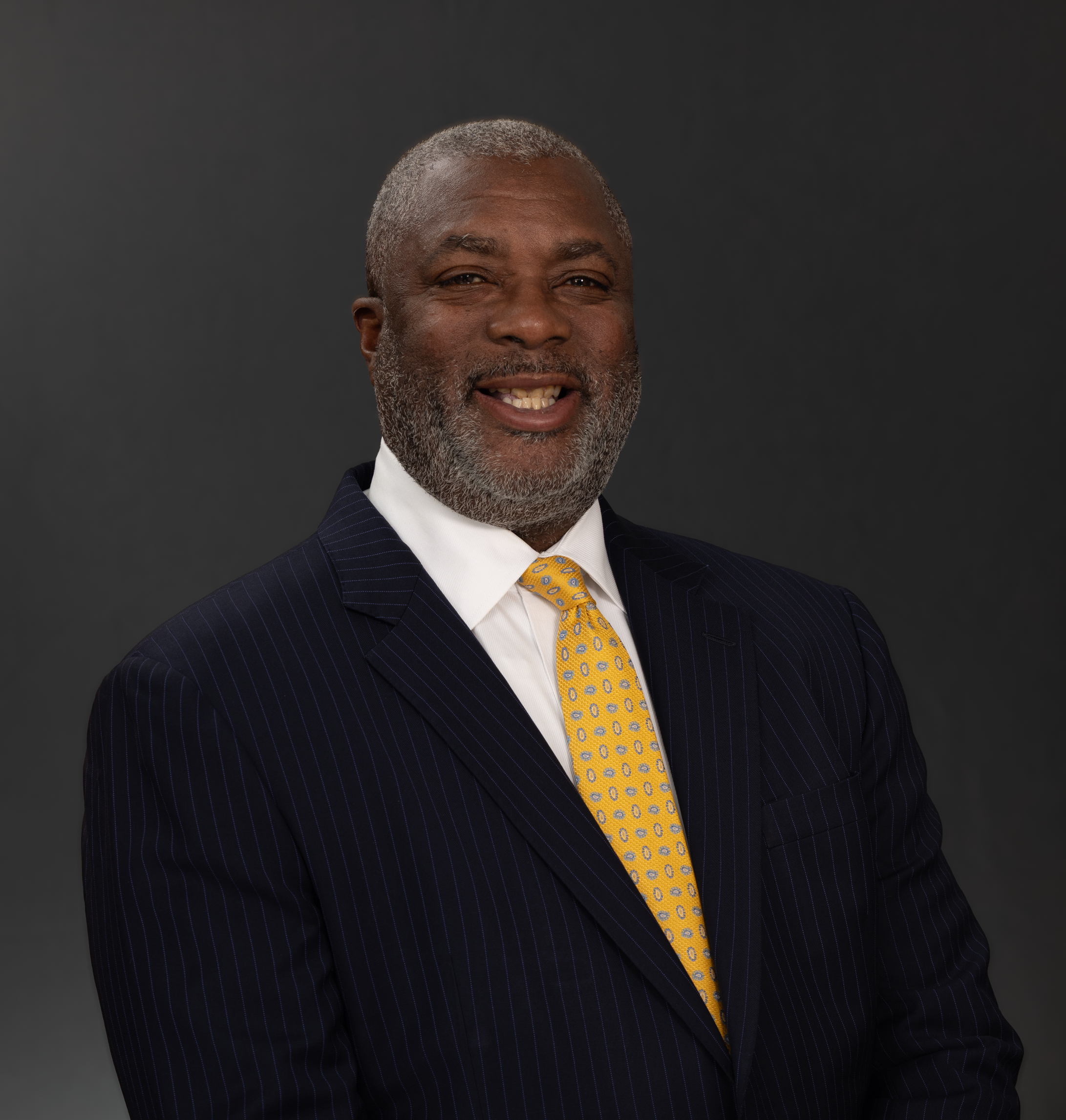 Confident businessman in a suit smiling against a dark background.