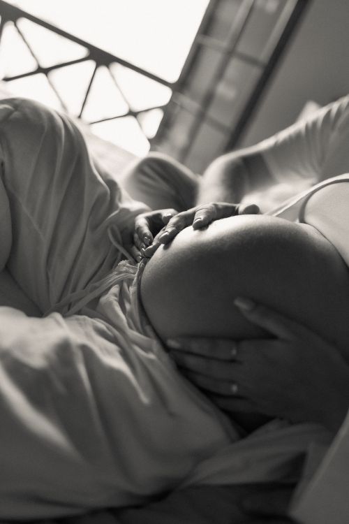 Free A serene black and white photo of a pregnant woman lying down, embracing her belly. Stock Photo