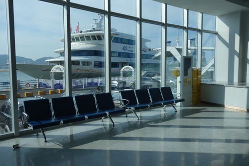 Free Interior of a ferry terminal with empty seats and a ferry visible outside, showcasing travel and transportation. Stock Photo