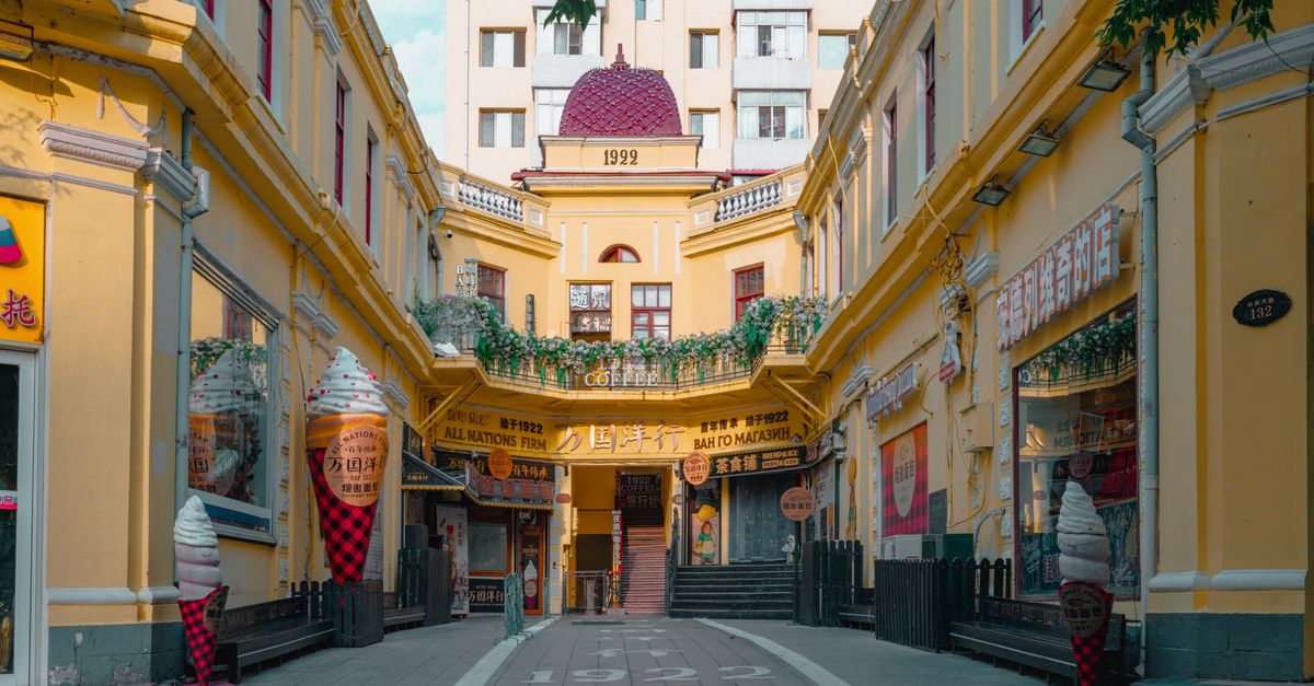 Charming alley between yellow buildings with ice cream decor in a historic area, sunny day.