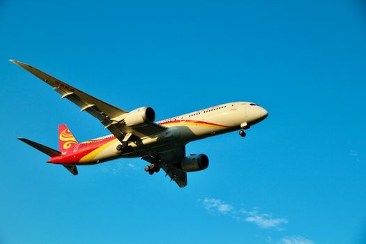 A vibrant image of a passenger airplane flying through a clear blue sky, showcasing its sleek design.