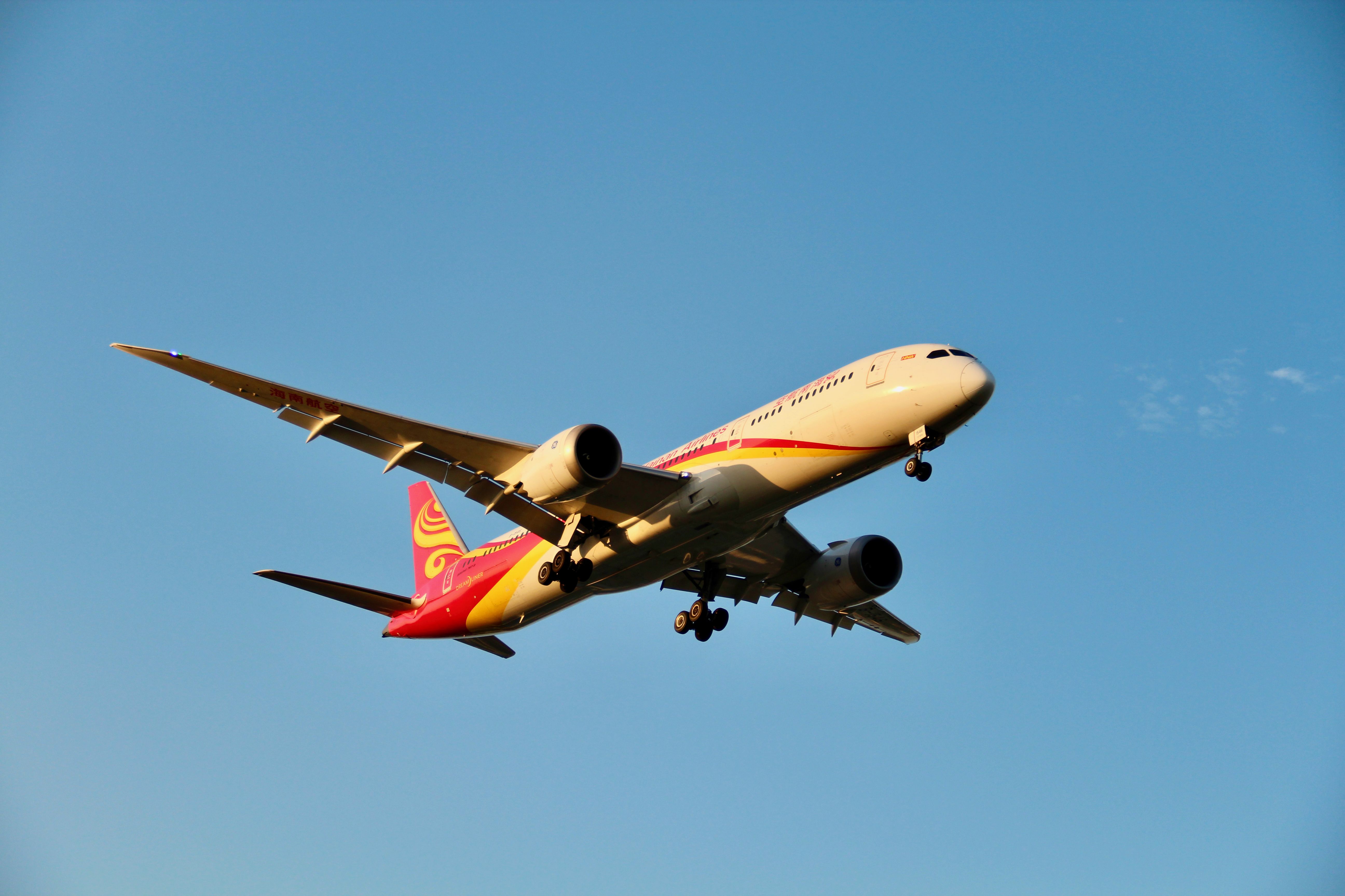 A commercial airplane flying against a clear blue sky during daytime.
