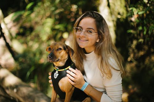 Free A joyful woman in glasses cuddling her small dog during a sunny day in the forest. Stock Photo