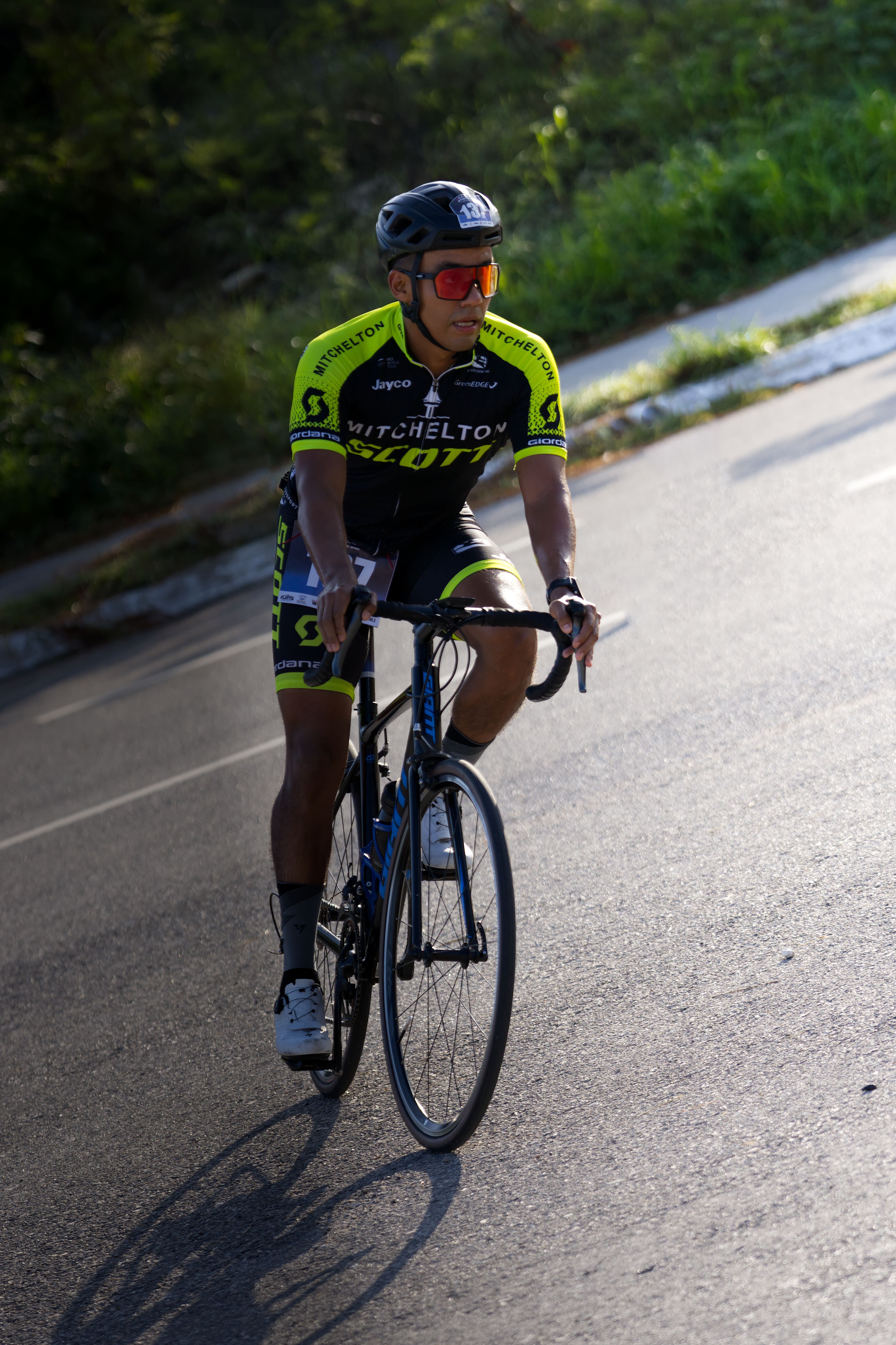Cyclist wearing a racing jersey rides on a sunny street in San Francisco de Campeche, Mexico.